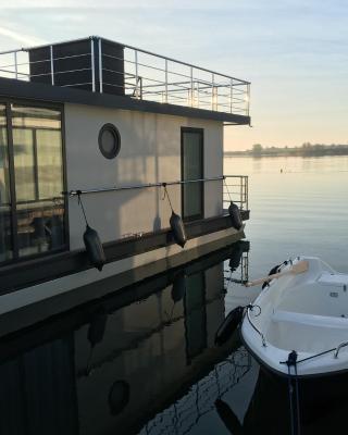 Modernes festliegendes Hausboot mit großzügiger Dachterrasse und Ruderboot