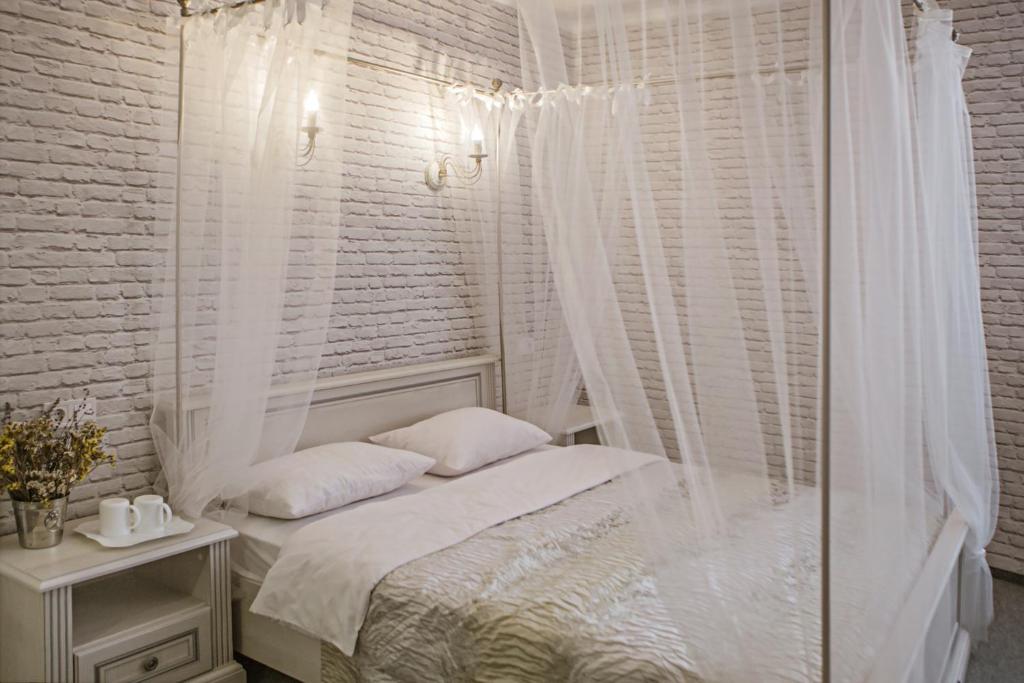 哈尔科夫利里维迷你酒店的白色卧室设有天蓬床和窗户