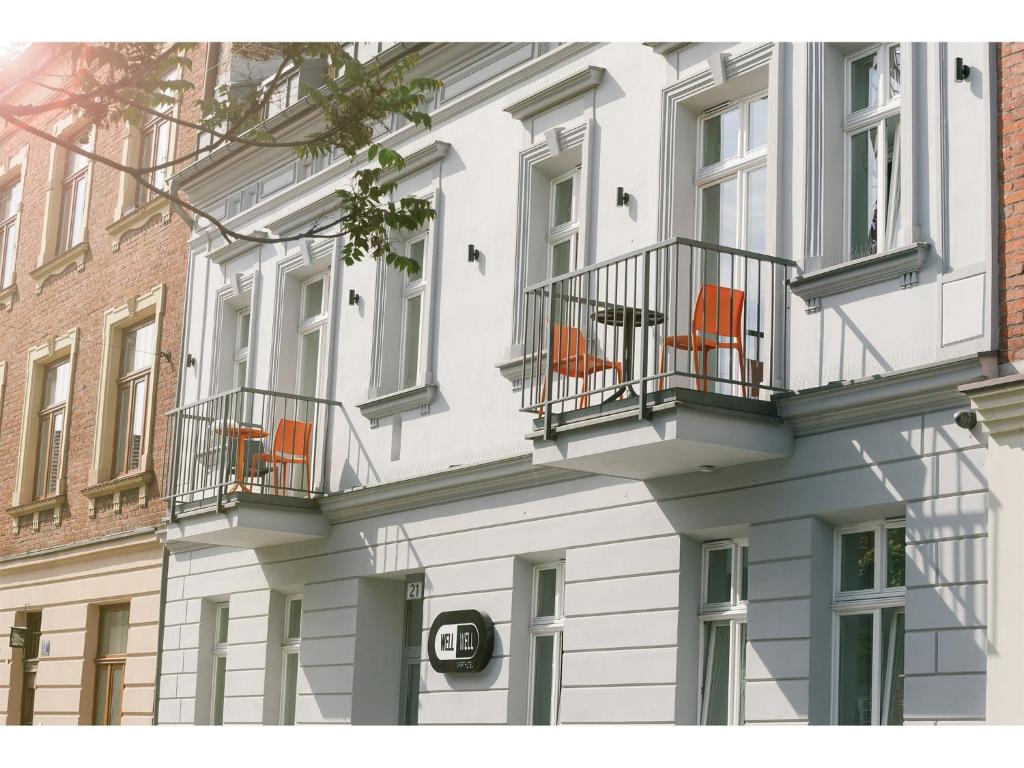 克拉科夫好好公寓式酒店的白色的建筑,阳台上摆放着橙色椅子