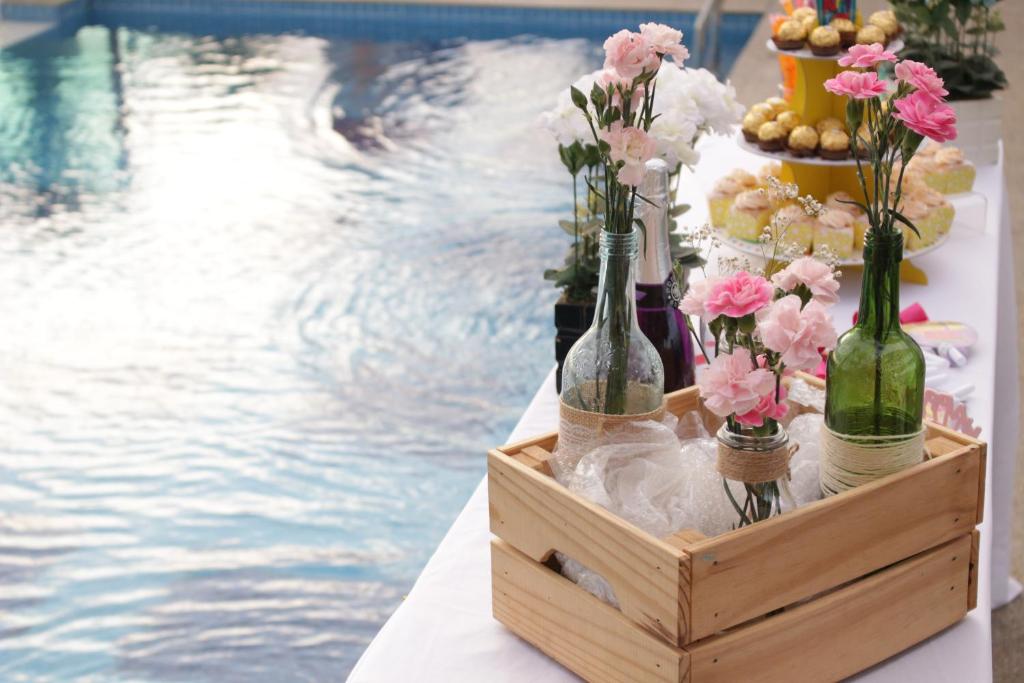 波德申天堂Spa酒店的游泳池旁的箱子里摆放着带瓶子和鲜花的桌子