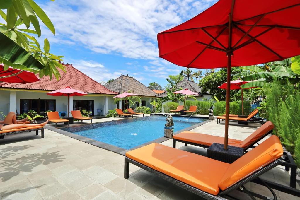 蓝梦岛娜拉达海滩民宿的一个带椅子和红伞的游泳池的度假酒店