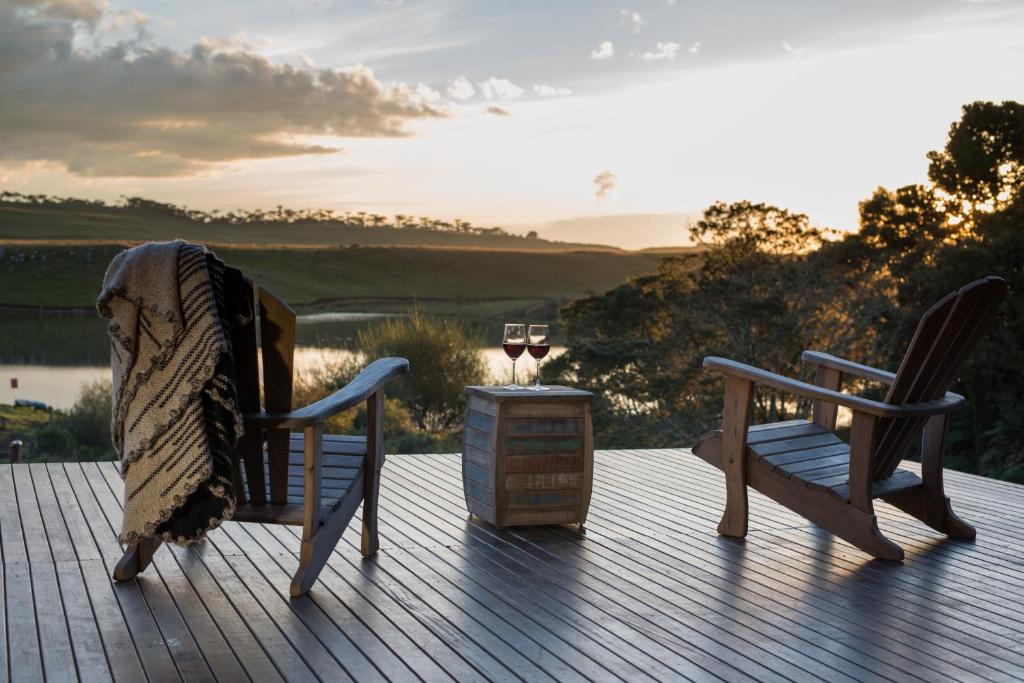 邦雅尔丁-达塞拉里约都拉斯特罗生态度假酒店的甲板上配有两把椅子和一张桌子,并备有一杯葡萄酒
