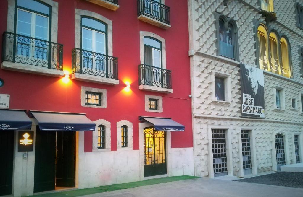 里斯本阿尔法玛滨江酒店的红色的建筑,设有窗户和阳台,位于街道上