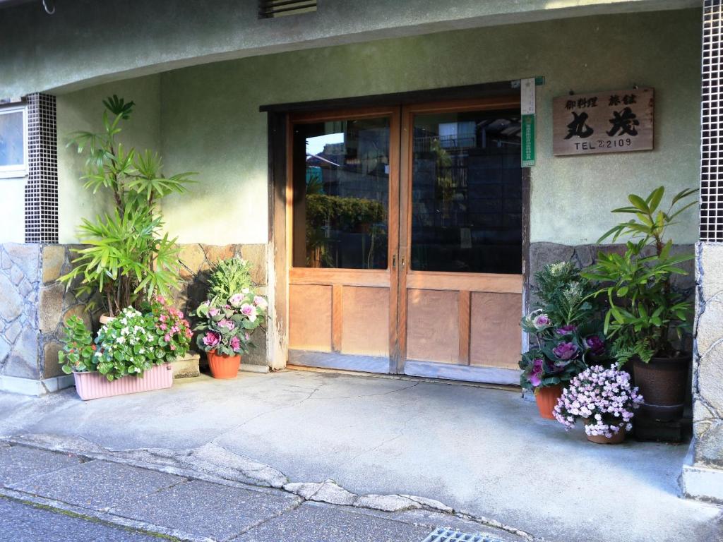 高岛市料理旅馆丸茂的一座有植物盆的建筑的前门