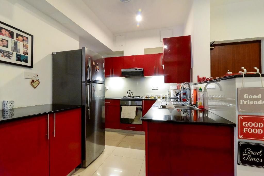 科伦坡320公寓的厨房配有红色橱柜和不锈钢冰箱