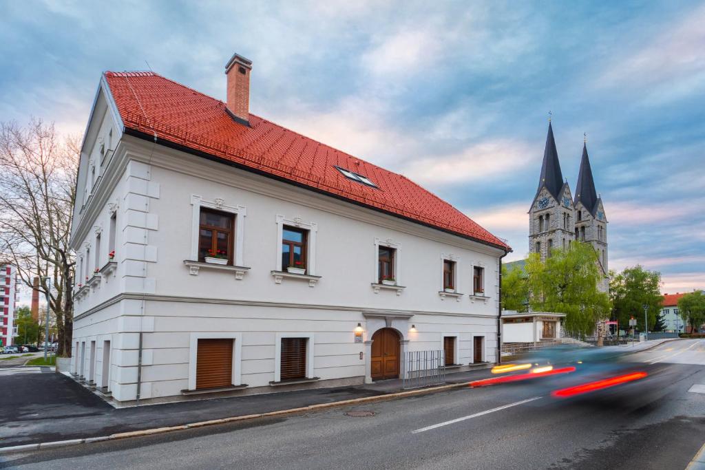 科切维Hostel Bearlog Kočevje的一座白色的建筑,有红色的屋顶和教堂