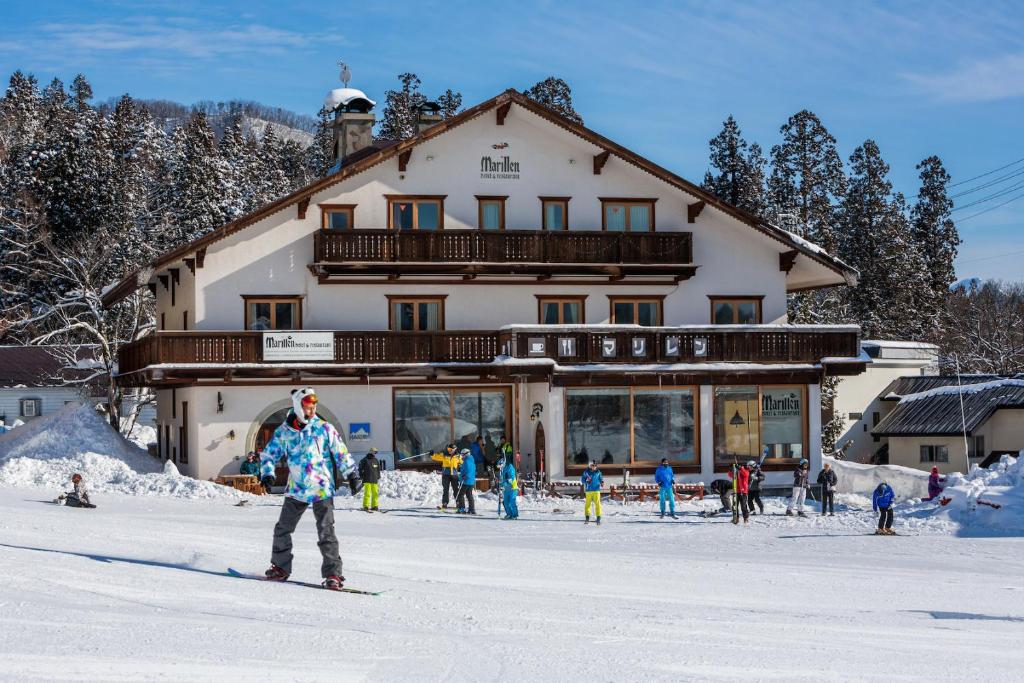 白马村Marillen Hotel by Hakuba Hospitality Group的一群人在滑雪小屋前滑雪