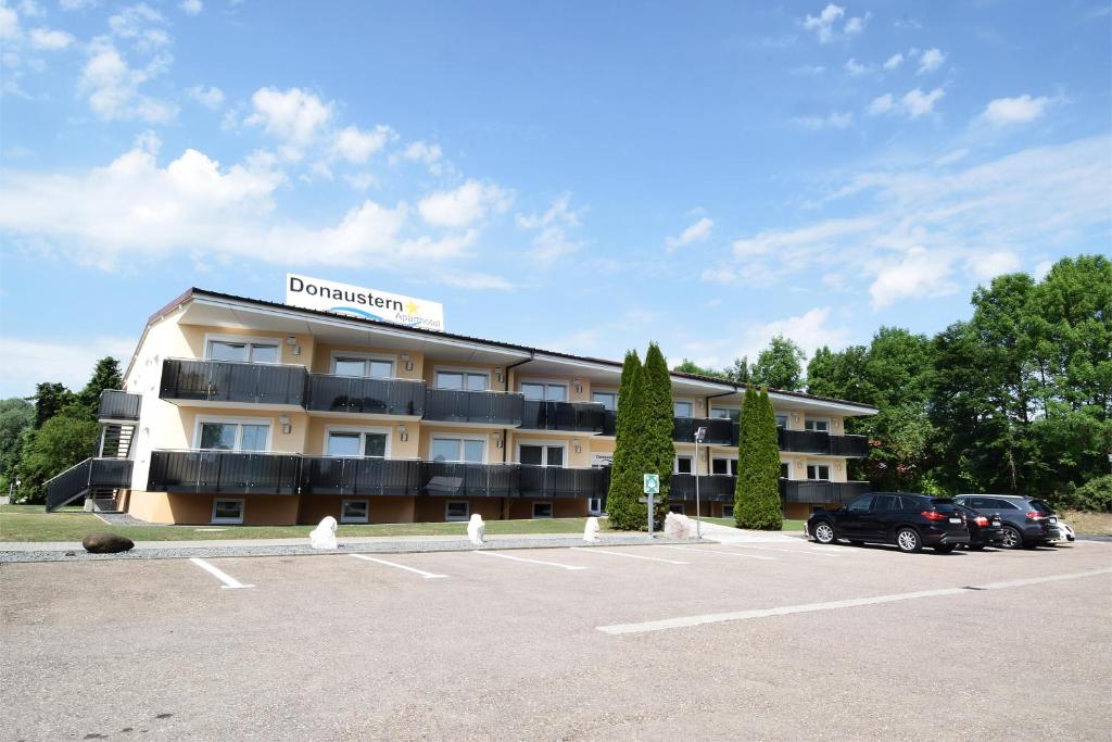 Asbach-Bäumenheim多瑙河之星公寓式酒店的停车场内有车辆的旅馆