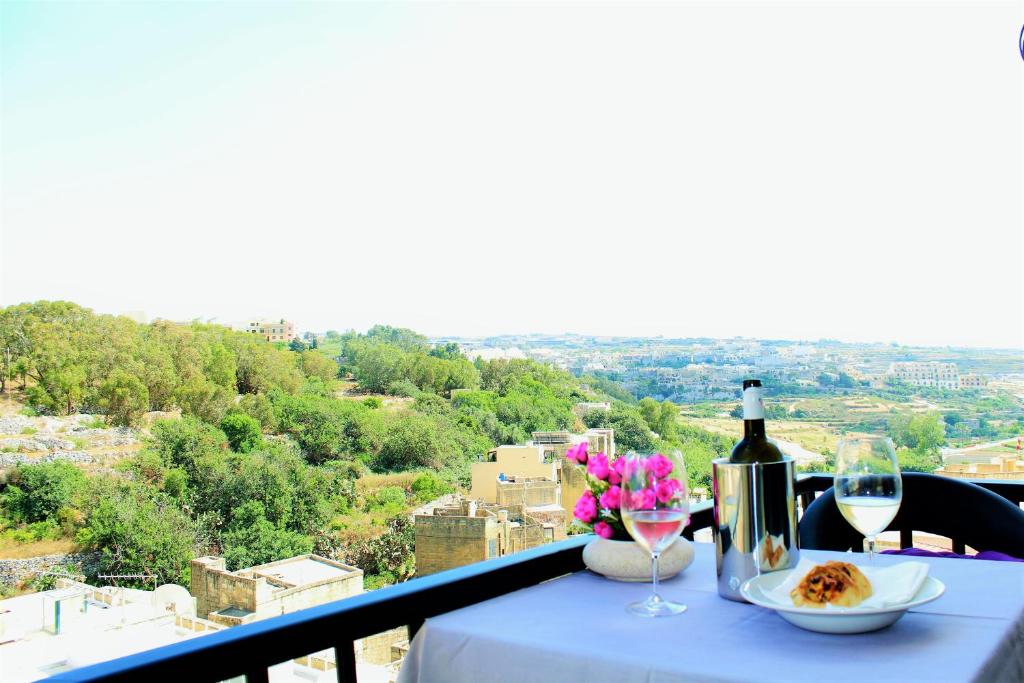 维多利亚Chimes - Gozo Bellevue Homes的阳台上的桌子上放着一杯葡萄酒和鲜花