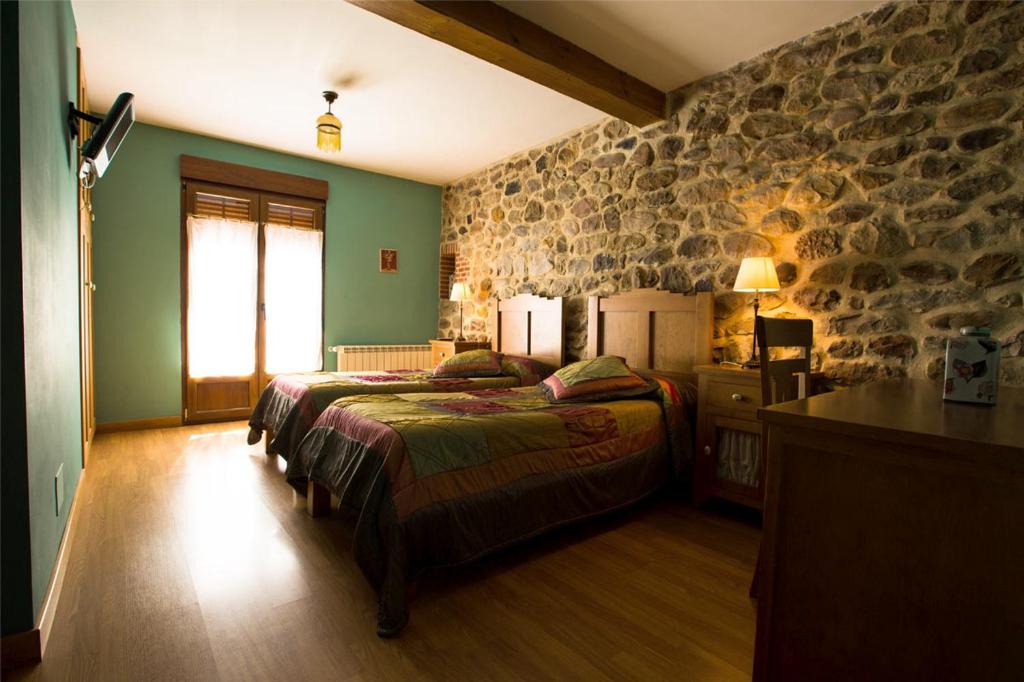 Arenas de IguñaPosada El Arrabal的一间卧室设有一张床和石墙