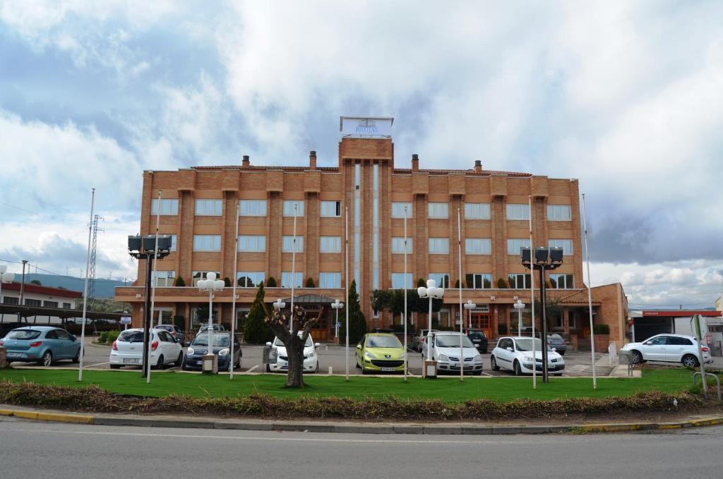 塔拉桑纳阿拉贡布鲁哈斯伊露酒店的一座大型砖砌建筑,停车场内有车辆停放