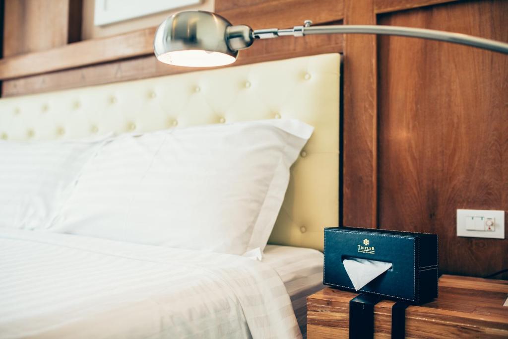 是拉差三B精品酒店的一间卧室,配有一张带灯和书籍的床