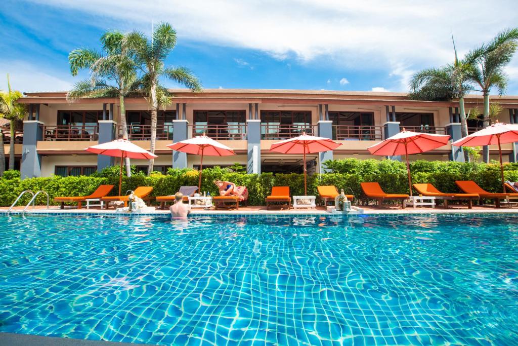 哈林海滩Sunrise Resort- Koh Phangan - SHA Extra Plus的酒店前方的游泳池配有椅子和遮阳伞