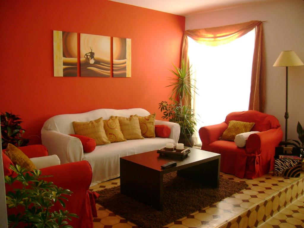 米纳斯米纳斯酒店的客厅配有白色沙发和2把红色椅子