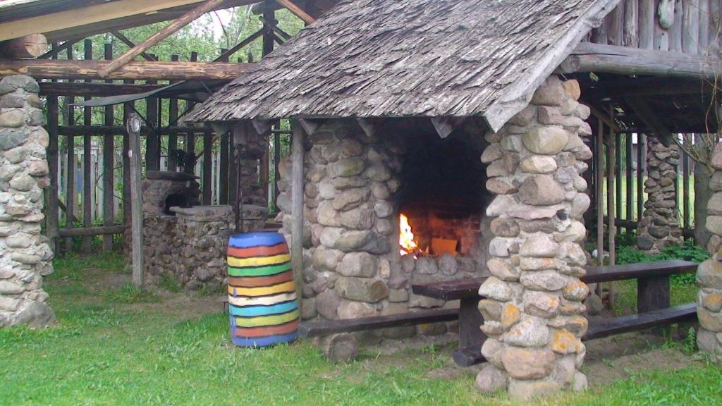 MammasteTammeKännu Kämpingud的一座小石头建筑,设有壁炉和一堆木柴