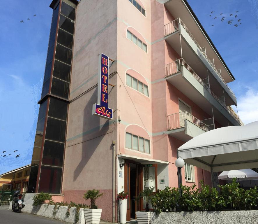 菲纳莱利古雷里兹酒店 的粉红色的建筑,前面有酒店标志