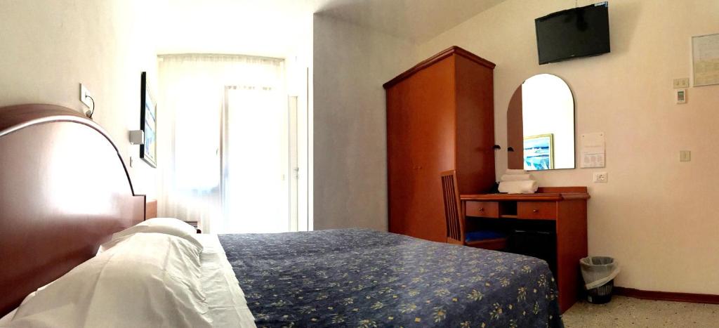 利尼亚诺萨比亚多罗Hotel Villa Candia的一间卧室配有一张床、梳妆台和镜子