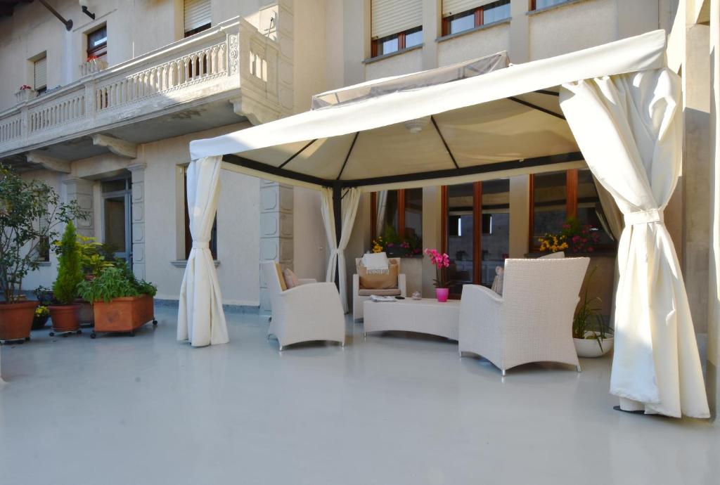 Romagnano SesiaIl Terrazzo B&B的庭院配有白色的椅子和遮阳伞。