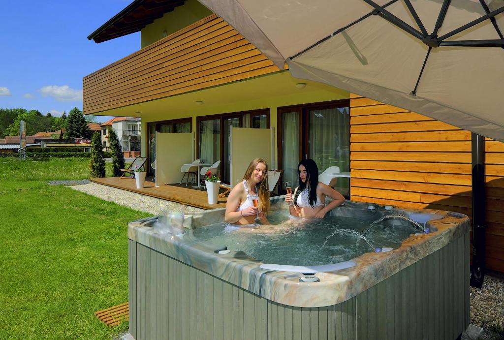 利普托斯基米库拉斯AHA Jasná Apartmány的两个女人坐在后院的热水浴缸里
