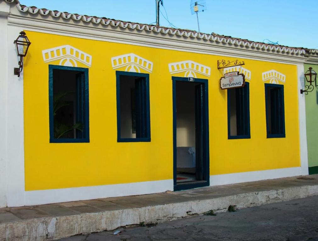 里奥迪孔塔斯Pousada Sempreviva的街道上一座黄色建筑,有黑色窗户