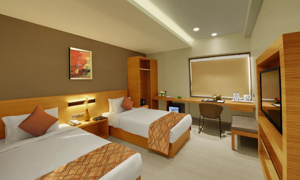 巴罗达Hotel Suba Elite Vadodara的酒店客房配有两张床和一张书桌