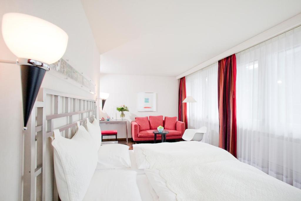 圣加仑Hotel Metropol的酒店客房,设有两张床和一张红色椅子