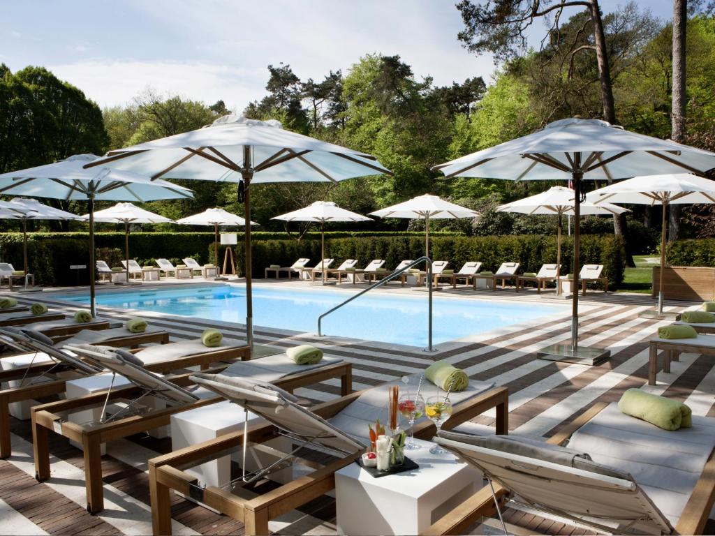 埃尔默洛罗莱夏朵精品酒店集团罗德科佩尔庄园酒店的一个带躺椅和遮阳伞的游泳池