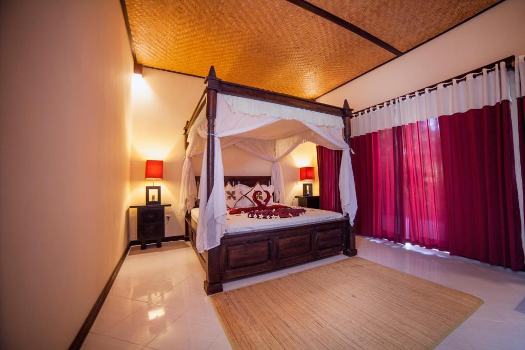 佩母德兰曼斯小屋及Spa酒店的一间卧室配有一张带红色窗帘的天蓬床