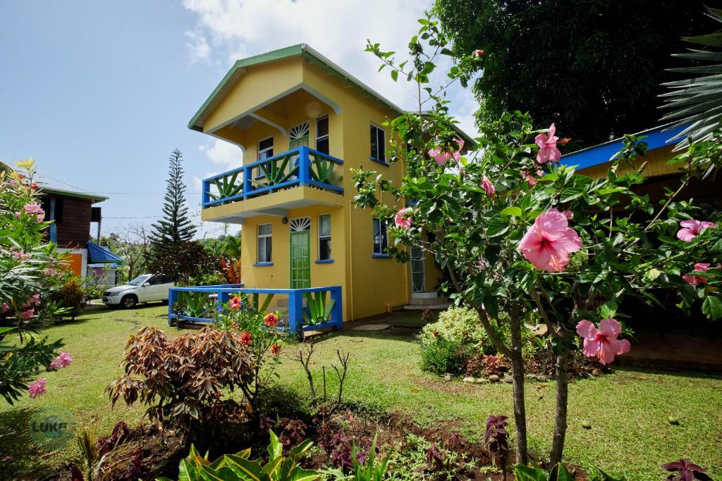 Calibishie杰克维旅馆的黄色的房子,设有蓝色的阳台和粉红色的鲜花