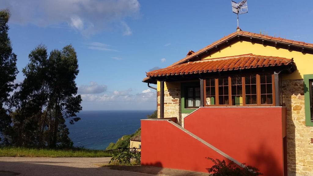 比利亚维西奥萨Turismo rural El Piensu的一座山丘上的房屋,背景是大海