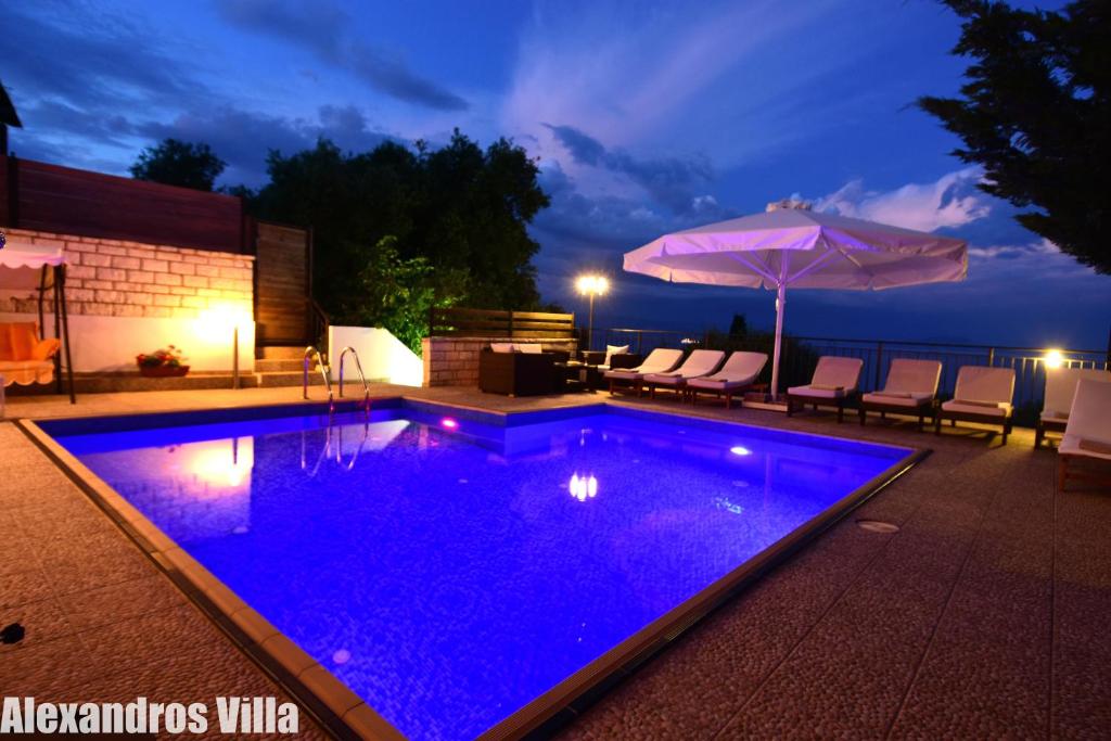 帕拉马Alexandros Villa Luxury Achiilion Corfu的后院的游泳池,晚上有蓝色的灯光