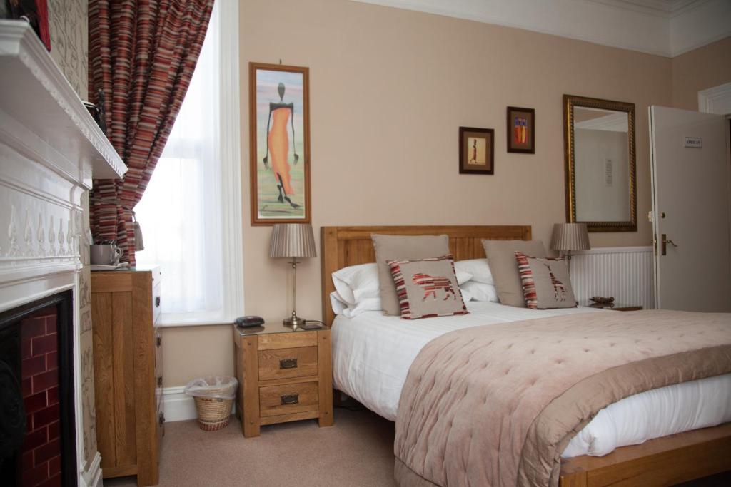 伊斯特布恩The Langtons Bed & Breakfast的一间卧室设有一张大床和一个壁炉