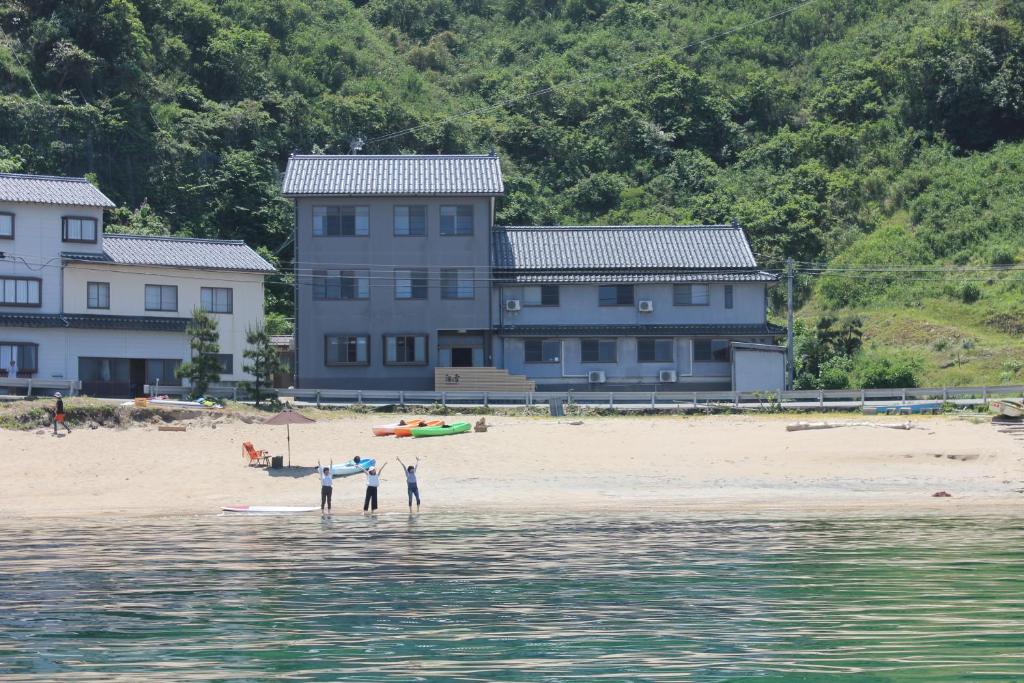 丰冈市海之声日式旅馆的一群人站在海滩上,有房子