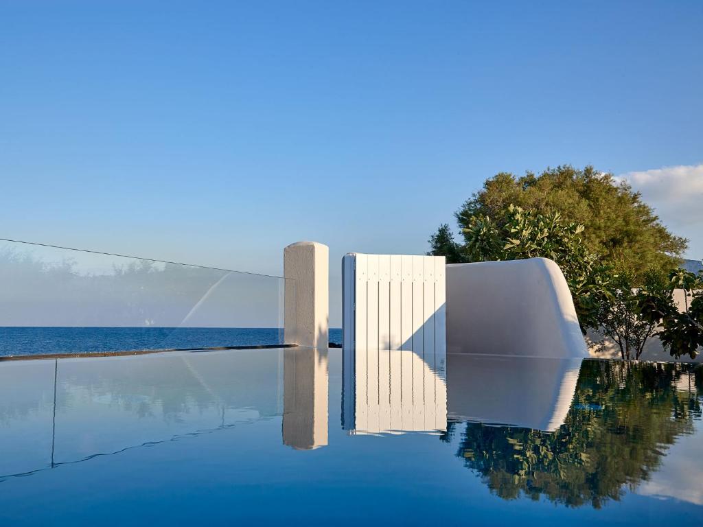 卡马利Incognito Beach Villa Santorini的一个带白色椅子和水的游泳池