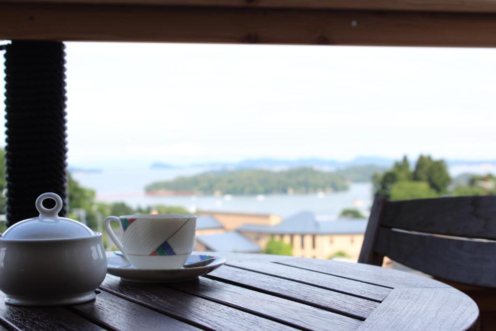 松岛町松岛阿巴小酒馆贝提酒店的茶壶和木桌上的一杯