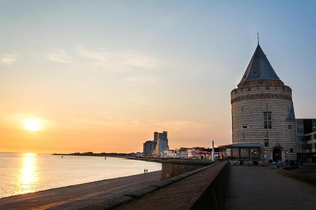 弗利辛恩德格文根托雷恩套房住宿加早餐旅馆的海滩上的建筑,背面是日落