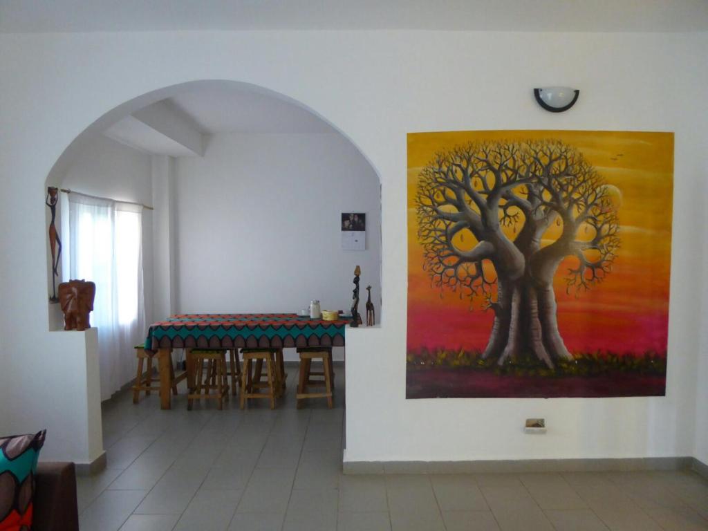 AmpayaSarawally Guesthouse的墙上挂有树画的饭厅