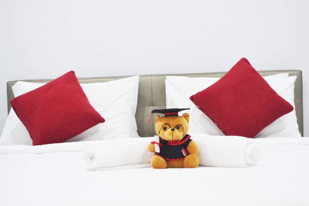 彭亨假期套房度假屋的戴毕业帽的泰迪熊坐在床上