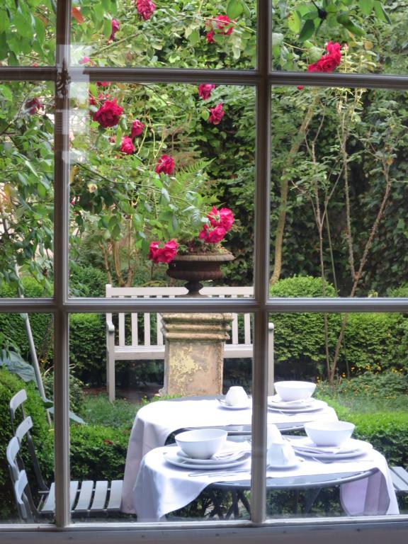 布鲁日阿莱格里亚酒店的一张桌子,上面放着白色的菜肴,一束玫瑰花穿过窗户