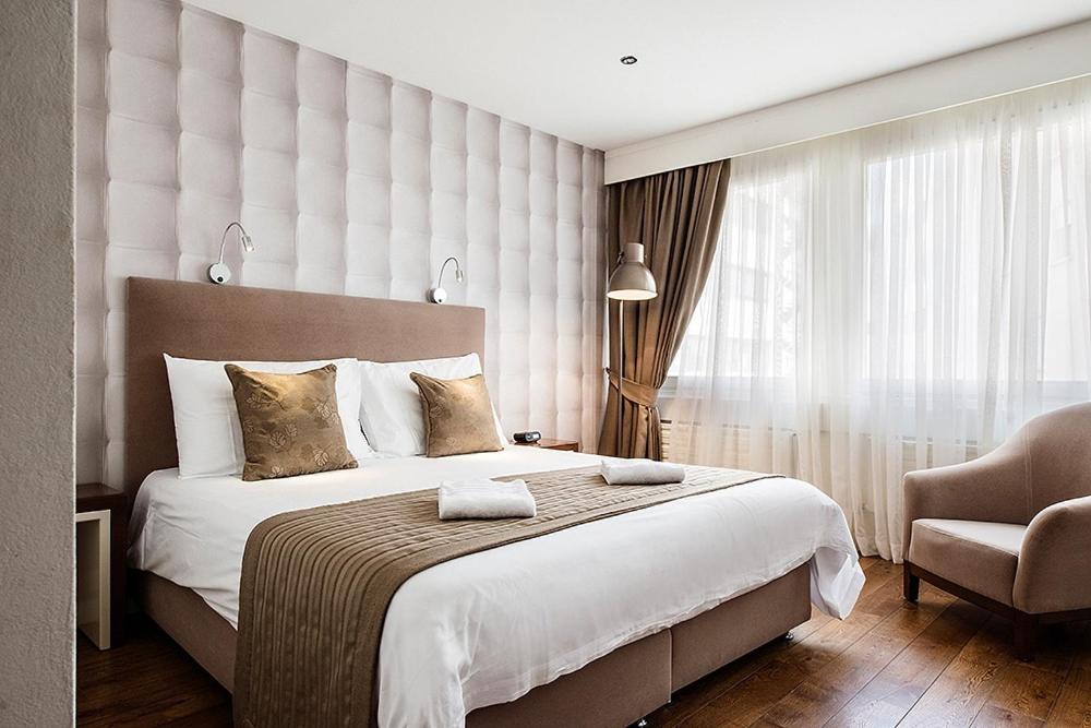 弗里堡阿尔法酒店的卧室配有一张白色大床和一把椅子