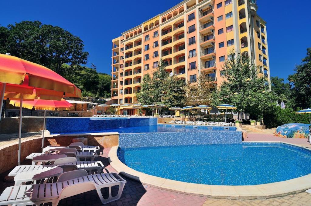 金沙Kris Apartments at Paradise Green Park的一座带游泳池和椅子的酒店和一座建筑