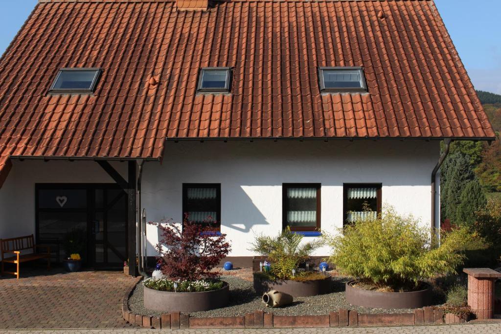 OsterbrückenFerienwohnung Zoe的一座有红色屋顶和一些植物的房子