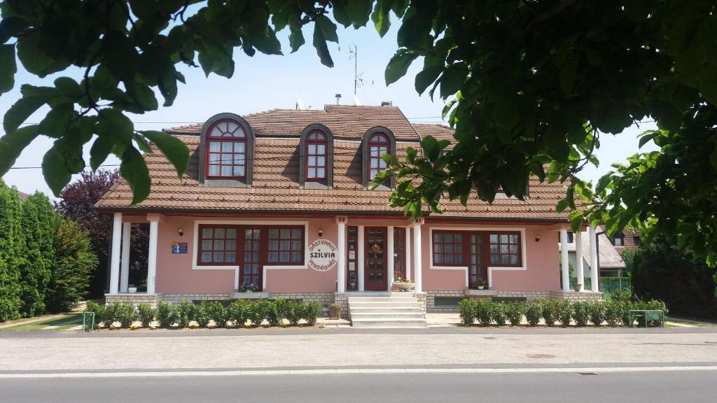 比克Szilvia Gästehaus的粉红色的房子,有棕色的屋顶