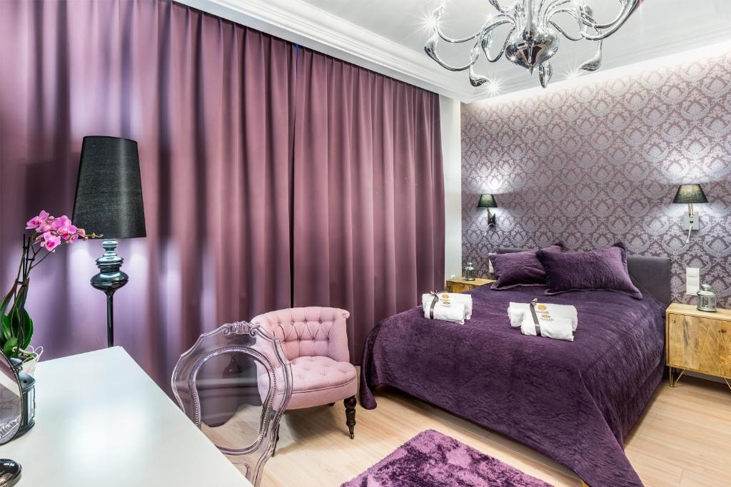 索波特Sea Sail Apartments的紫色卧室配有一张床和一把椅子