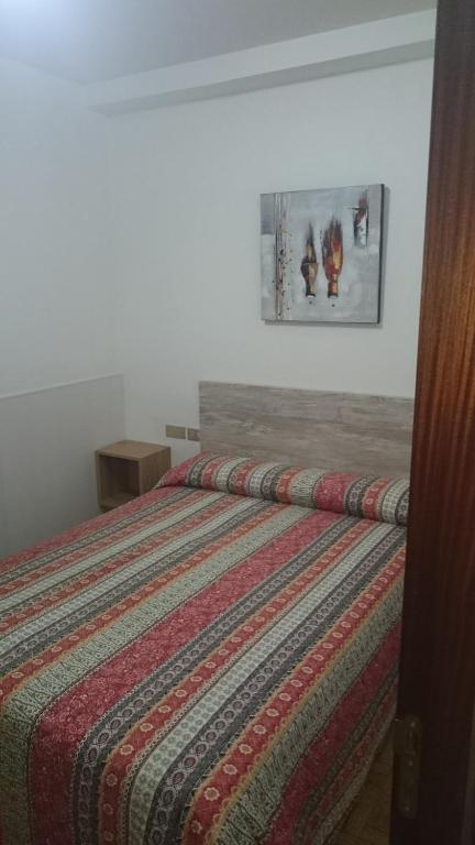 雷东德拉巴伊亚德查佩拉旅馆的卧室内的一张带条纹棉被的床