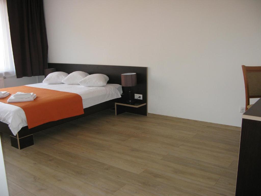Dobele多贝勒酒店的酒店客房,配有一张带橙色毯子的床