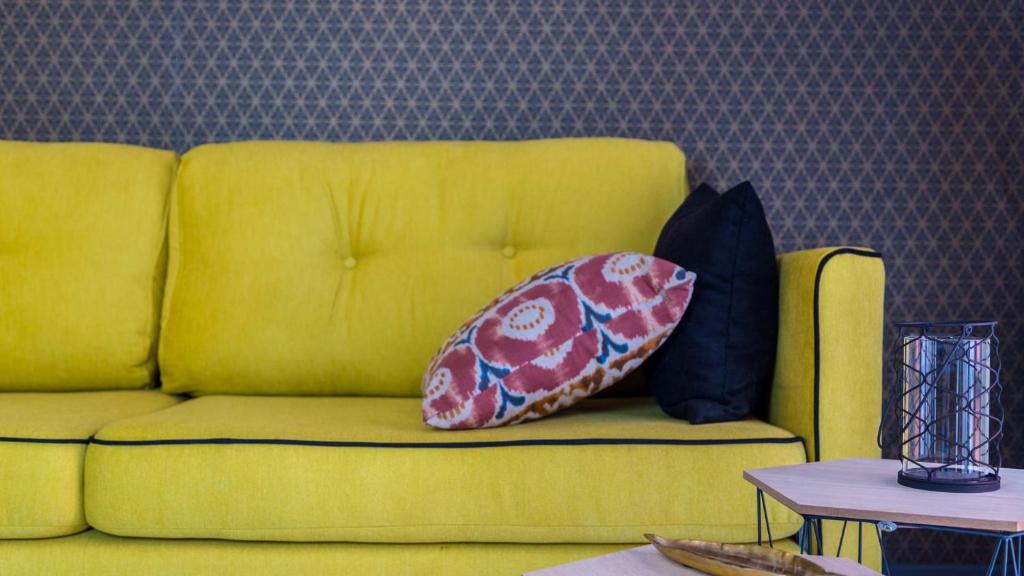 塞奥-德乌赫尔Groc Rooms的一张黄色的沙发,上面有两个枕头