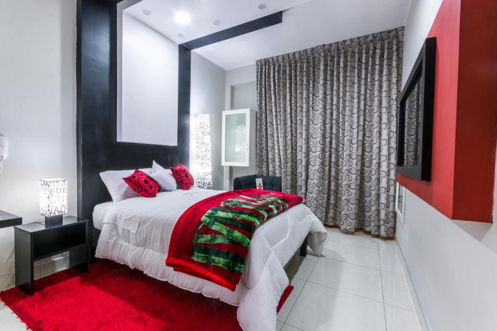 瓦拉斯Hotel El Rubi的一间卧室配有一张带红色毯子的大床