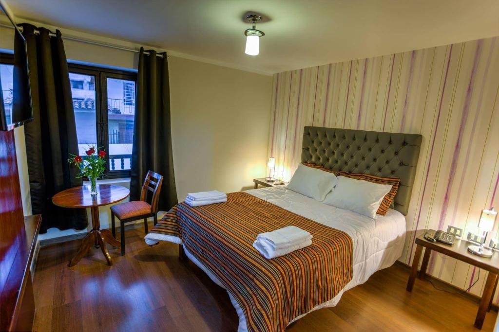 库斯科Ureta Hotel的一间卧室配有一张床、一张桌子和一个窗户。