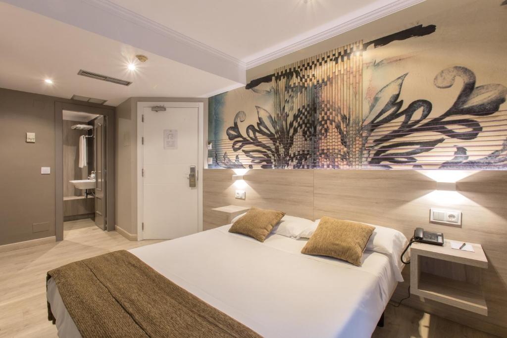 圣地亚哥－德孔波斯特拉阿尔达圣卡洛斯酒店的卧室配有一张大床,墙上挂有绘画作品
